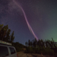 A pink Steve against a dark sky with green northern lights.